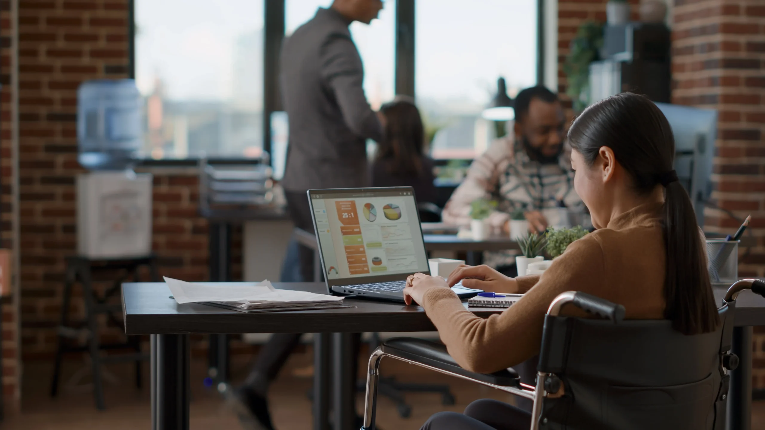 asian-woman-greeting-office-colleagues-arriving-work-getting-ready-plan-marketing-presentation-female-employee-using-laptop-analyze-financial-charts-startup-growth (1)-min_11zon